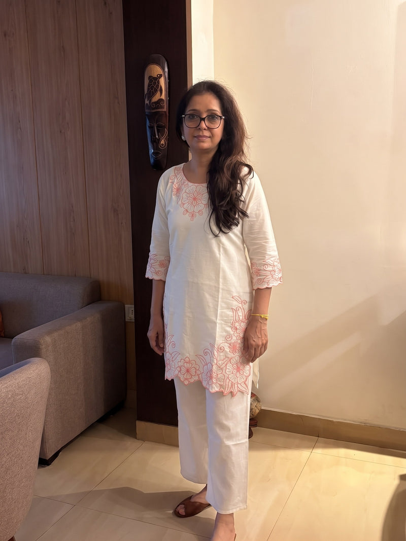 Customer wearing an ivory kurta set with pink floral embroidery and white palazzo trousers