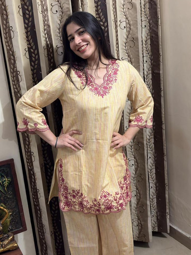Customer wearing a pale yellow co-ord set with pink floral embroidery and a scalloped hem